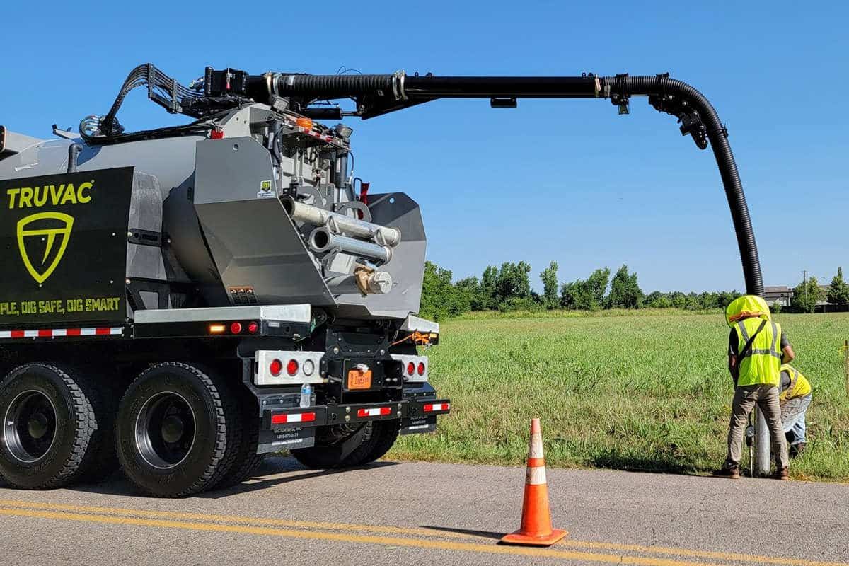 Hydrovac vacuum excavation truck with its boom extended, daylighting a utility beside a road